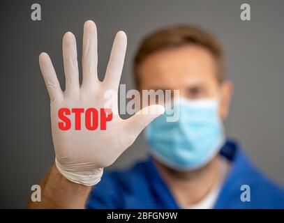 COVID-19 Ausbruch. Arzt oder Krankenschwester mit chirurgischer Gesichtsmaske und Handschuhen PSA, die Hand in STOPPGESTE zeigt. Helfen Sie, die Kampagne zur Verbreitung von Viren zu stoppen Stockfoto