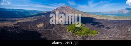 Luftaufnahme von erstarrten schwarzen vulkanischen Lavaströmen um die Hänge eines aktiven Vulkans. (Mount Batur) Stockfoto