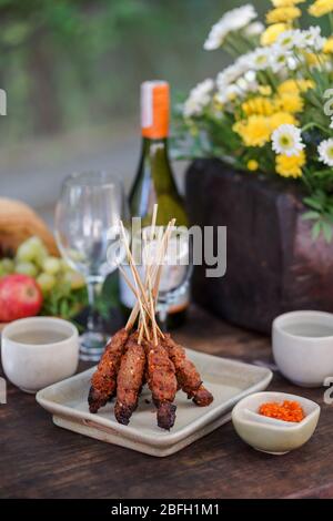 Auf einzigartige Weise wird Hähnchen-Satay auf einem Holztisch serviert. Stockfoto