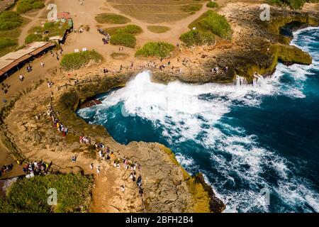 Luftaufnahme von Menschen, die sich versammeln, um riesige Wellen des Ozeans gegen eine felsige Inselküste zu brechen (Devil's Tears, Nusa Lembongan, Indonesien) Stockfoto