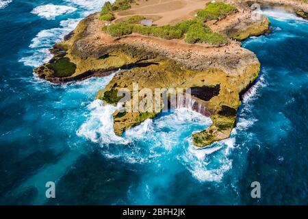Luftaufnahme von riesigen Wellen, die in eine felsige Küste auf einer tropischen Insel stürzen (Teufelstränen, Nusa Lembongan) Stockfoto