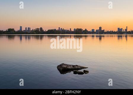 Skyline der Stadt Rotterdam, Niederlande kurz nach Sonnenuntergang. Schöne Spiegelungen der Gebäude und Himmel im See 'Kralingse Plas'. Stockfoto