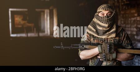 Arabischer Soldat im Kopfschmuck aus dem Nationalkeffiyeh mit einer Waffe in den Händen. Muslimischer Mann mit einer Pistole auf schwarzem Hintergrund. Stockfoto