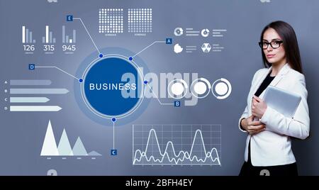 Geschäftsfrau in Brille stehend mit holographischen Graphen Stockfoto
