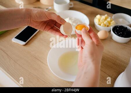 Nahaufnahme Frau Hände brechen Hühnereier in einem Teller in der Küche. Teig kochen. Stockfoto