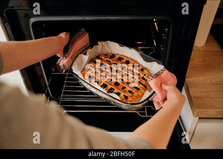 Frau Hand Backblech mit leckeren Kuchen aus dem Ofen. Stockfoto