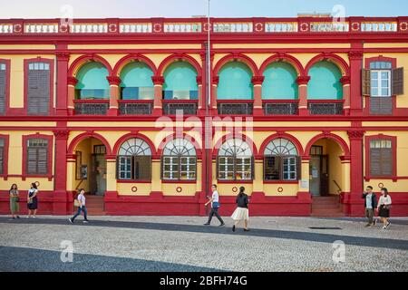 Menschen, die am farbenfrohen Gebäude der Zentralbibliothek von Macao spazieren. Macau, China. Stockfoto