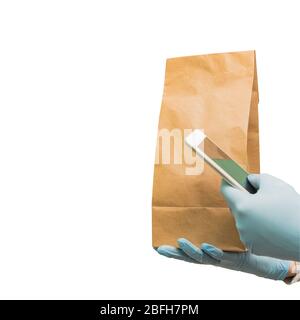 Lieferung von Lebensmitteln ohne Kontakt. Lieferung Frau hält smatphone und Papier Handwerk Tasche mit Essen zum Mitnehmen. Soziale Distanzierung während einer Coronavirus-Pandemie Stockfoto