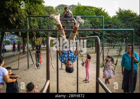 Kinder spielen auf den Affenbars im Mahabandoola Garden, Yangon, Myanmar Stockfoto