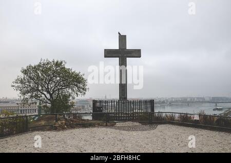 Budapest, Ungarn - 6. November 2019: Kreuzdenkmal auf dem Gellert-Hügel in der ungarischen Hauptstadt. Donau und die Altstadt im Hintergrund. Bewölktes Wetter, wolkiger Himmel. Christliches, religiöses Konzept. Stockfoto