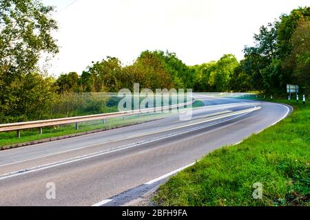 Langsame Verschlusszeit für Bewegungsunschärfe des Autos auf der Landstraße bei Tag Stockfoto