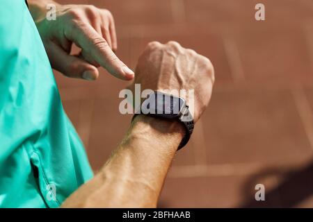 Mann, der seine Smartwatch anschaut, während er draußen trainiert. Nahaufnahme des Mannes mit seiner Smart Watch App. Gesunde Lebensweise Stockfoto
