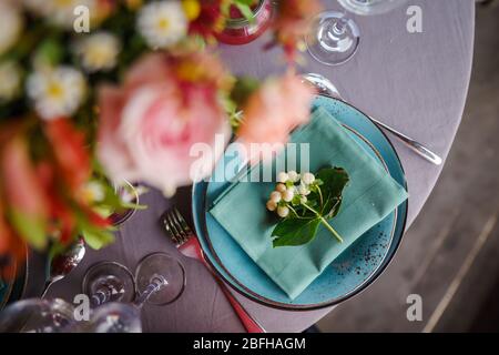 Keramikplatten und anderes Besteck sind auf einem Holztisch mit weichen Tischdecken für ein luxuriöses Mittagessen angeordnet. Stockfoto