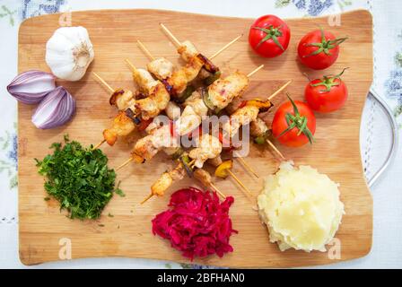 Set von Shish Kebabs . Beef Kebab auf einem Holzbrett . Rotkohl Sauerkraut . Kartoffelpüree . Knoblauch, Zwiebeln, Tomaten. Gehackter Koriander . Lamm Stockfoto