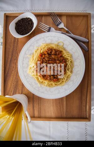 Spaghetti Bolognese mit Hackfleisch, Zwiebel, gehackte Tomaten, Tomatenmark . Rohe Spaghetti-Pasta in einer Schüssel. Schwarzer Pfeffer, Mayonnaise in einer Schüssel Stockfoto