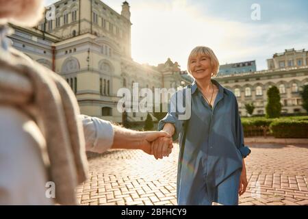 Die beste Frau aller Zeiten! Schönes älteres Paar, das an einem sonnigen Tag im Freien tanzt und die Hände hält. Viel Spaß. Liebeskonzept. Glückliche Momente Stockfoto