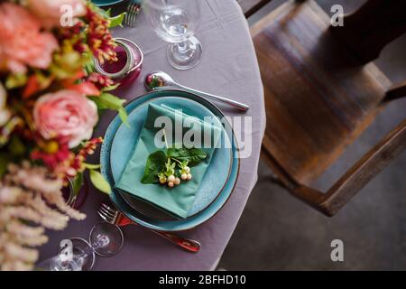 Keramikplatten und anderes Besteck sind auf einem Holztisch mit weichen Tischdecken für ein luxuriöses Mittagessen angeordnet. Stockfoto