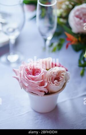 Einige rosa Rosen werden in einer kleinen Vase auf dem Tisch platziert. Stockfoto