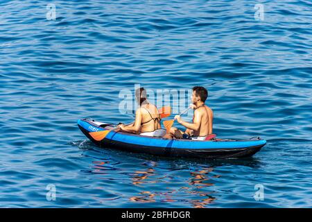 Ein junges Paar, ein Mann und eine Frau paddeln auf einem aufblasbaren Kajak im blauen Meer. Golf von La Spezia, Ligurien, Italien, Europa Stockfoto