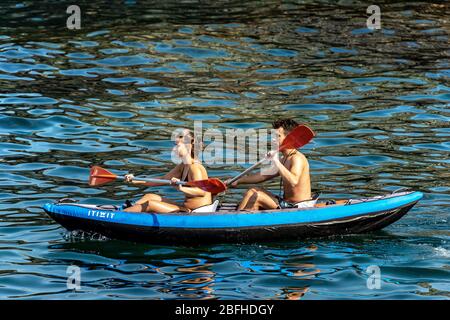 Ein junges Paar, ein Mann und eine Frau paddeln auf einem aufblasbaren Kajak im blauen Meer. Golf von La Spezia, Ligurien, Italien, Europa Stockfoto