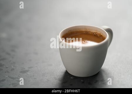 Heißer Espresso in weißer Tasse auf betontem Hintergrund mit Kopie Platz Stockfoto