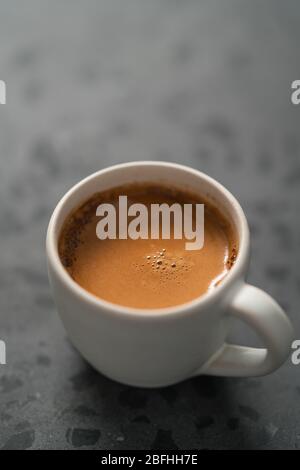 Heißer Espresso in weißer Tasse auf betontem Hintergrund mit Kopie Platz Stockfoto