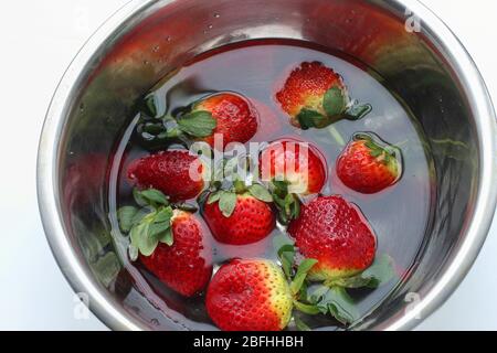 Frische Erdbeeren in Edelstahlschüssel einweichen, isoliert auf weißem Hintergrund Stockfoto