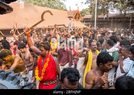 Anhänger im roten Kleid und Sickleshaped Schwerter am Sree Kurumba Sree Kurumba Bhagwati Tempel Kodungallur, während Bharani Festival, Thrissur, Kerala, Indien Stockfoto