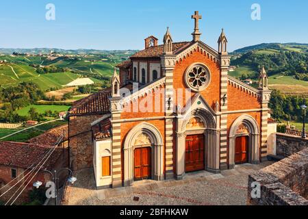 Blick auf kleine Pfarrkirche und Hügel mit grünen Weinbergen im Hintergrund in Piemont, Norditalien. Stockfoto