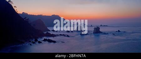 Panoramablick auf Klippen bei Sonnenuntergang mit verschiedenen Felsen im Meer. Der Strand der Stille, Asturien. Stockfoto