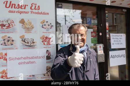 19. April 2020, Hessen, Frankfurt/Main: Corrado Spadotto, Geschäftsführer der Eisdiele Eis Christina, steht mit erhobenem Daumen vor seinem Laden. Ab Montag (20.04.2020) dürfen Eisdielen in Hessen sowohl Waren liefern als auch an der Theke verkaufen, allerdings nur im Out-of-Home-Verkauf und ohne Sitzplatzangebot. Um die Entfernungsregel einzuhalten, darf innerhalb eines Radius von 50 Metern kein Eis verzehrt werden. Foto: Frank Rumpenhorst/dpa Stockfoto