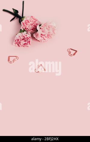 Rosen auf einem rosa Hintergrund mit drei Metallherzen. Stockfoto