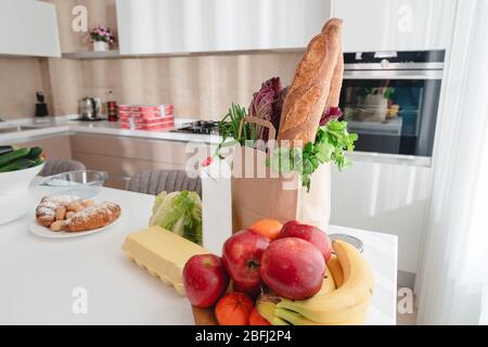 Papiertüte mit Gemüse und Brot, Lebensmittelgeschäft mit Kopierplatz auf Küchentisch Stockfoto