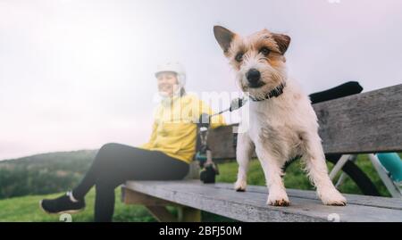 Asiatische Frau machen bergauf mit Mountainbike. Eine Frau, die mit einem Hund am Aussichtspunkt in Oamaru, Neuseeland, herumschaut. Stockfoto