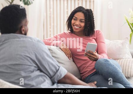 Junges afrikanisches Paar zu Hause plaudern, auf dem Sofa zusammen entspannen Stockfoto