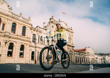 18/04/2020 Asiatische Frau Fahrrad fahren Pass historischen Gebäude an der Habour Street, Oamaru, Neuseeland. Stockfoto