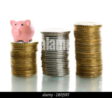 Sparschwein steht auf einem Stapel von Münzen isoliert auf weiß Stockfoto