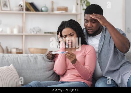 Unbeabsichtigte Schwangerschaft. Besorgt african american Paar mit positiven Testergebnisse verärgert Stockfoto