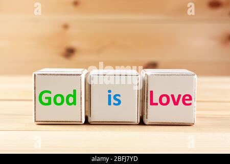 Gott ist Liebe Text geschrieben in Würfel auf Holzhintergrund Stockfoto