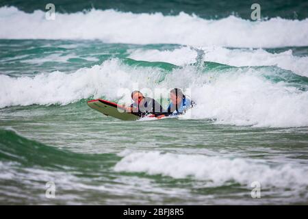 Cornish Surfers genießen das weiße Wasser Stockfoto