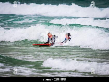 Cornish Surfers genießen das weiße Wasser Stockfoto