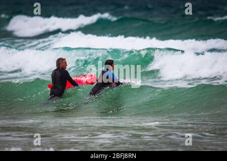 Cornish Surfers genießen das weiße Wasser Stockfoto