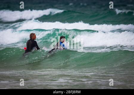 Cornish Surfers genießen das weiße Wasser Stockfoto