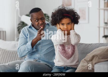 Wütend afroamerikanischen Großvater schreit seine Enkelin zu Hause, konzentrieren sich auf Kind Ohren schließen Stockfoto