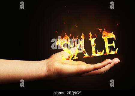 Hand mit Wort Verkauf aus Feuer Flamme isoliert auf schwarz Stockfoto