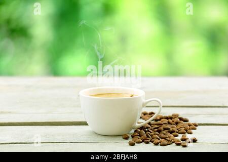 Tasse Kaffee auf Holztisch auf grünem Hintergrund Stockfoto