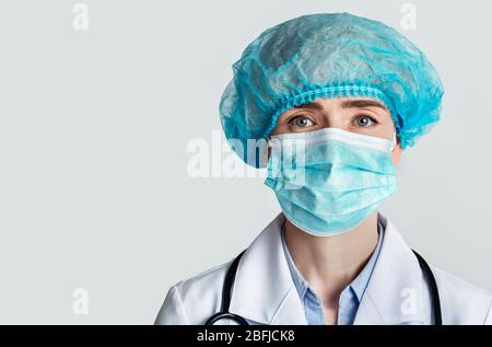 Therapeut in Schutzmaske und Kappe mit Stethoskop Stockfoto