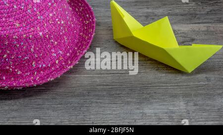 Origami, gelbes Schiff aus Papier und rosa Hut auf Holztisch, Hobby Stockfoto