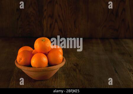 Viele Orangen auf der Schale - dunkler Hintergrund. Stillleben Früchte im Vintage-Stil. Orangen an der Schale dunkles Foto Stockfoto