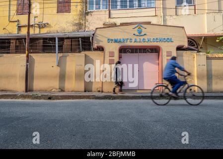 Kochi, Kerala, Indien - 4. April 2018: Das Eingangstor einer Schule mit einem Mädchen und einem Mann, der mit dem Fahrrad vorbeifährt, im historischen Viertel von Stockfoto